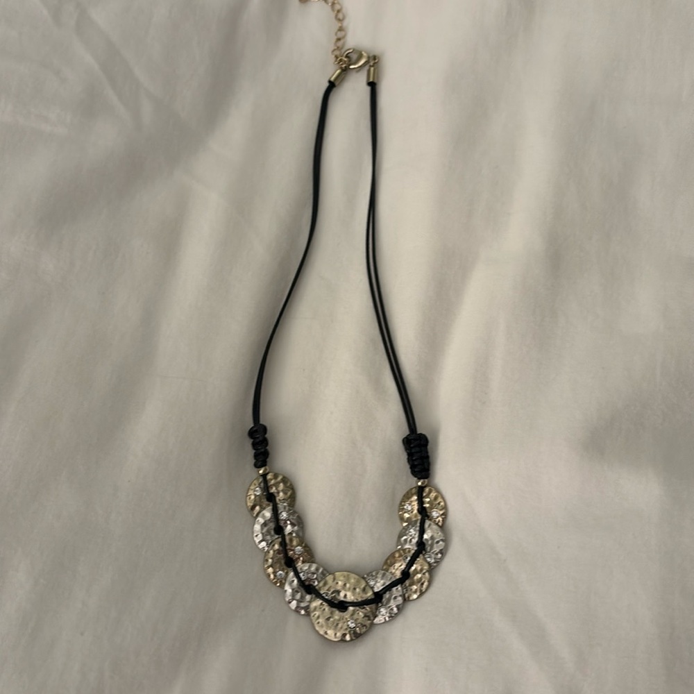 Black cord necklace with gold and silver disc at bottom of neck